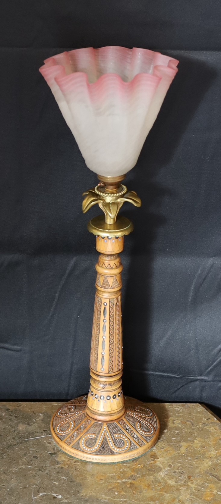 An early 20th century Danish carved and glass bead inset wood lamp base with brass flowerhead mount and associated tinted and frosted glass shade, height to top of shade 47cm
